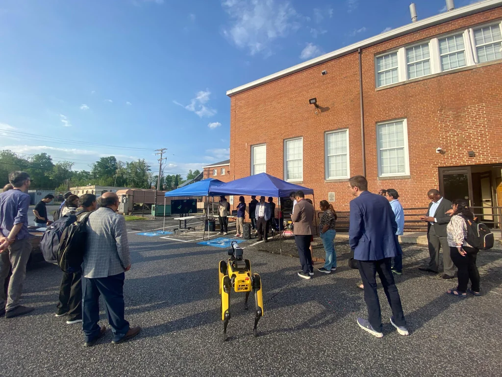 Participants gathered around a quadruped robot during an outdoor demonstration at UMBC